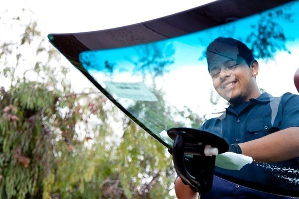 Auto glass expert repairing a cracked windshield on a vehicle.