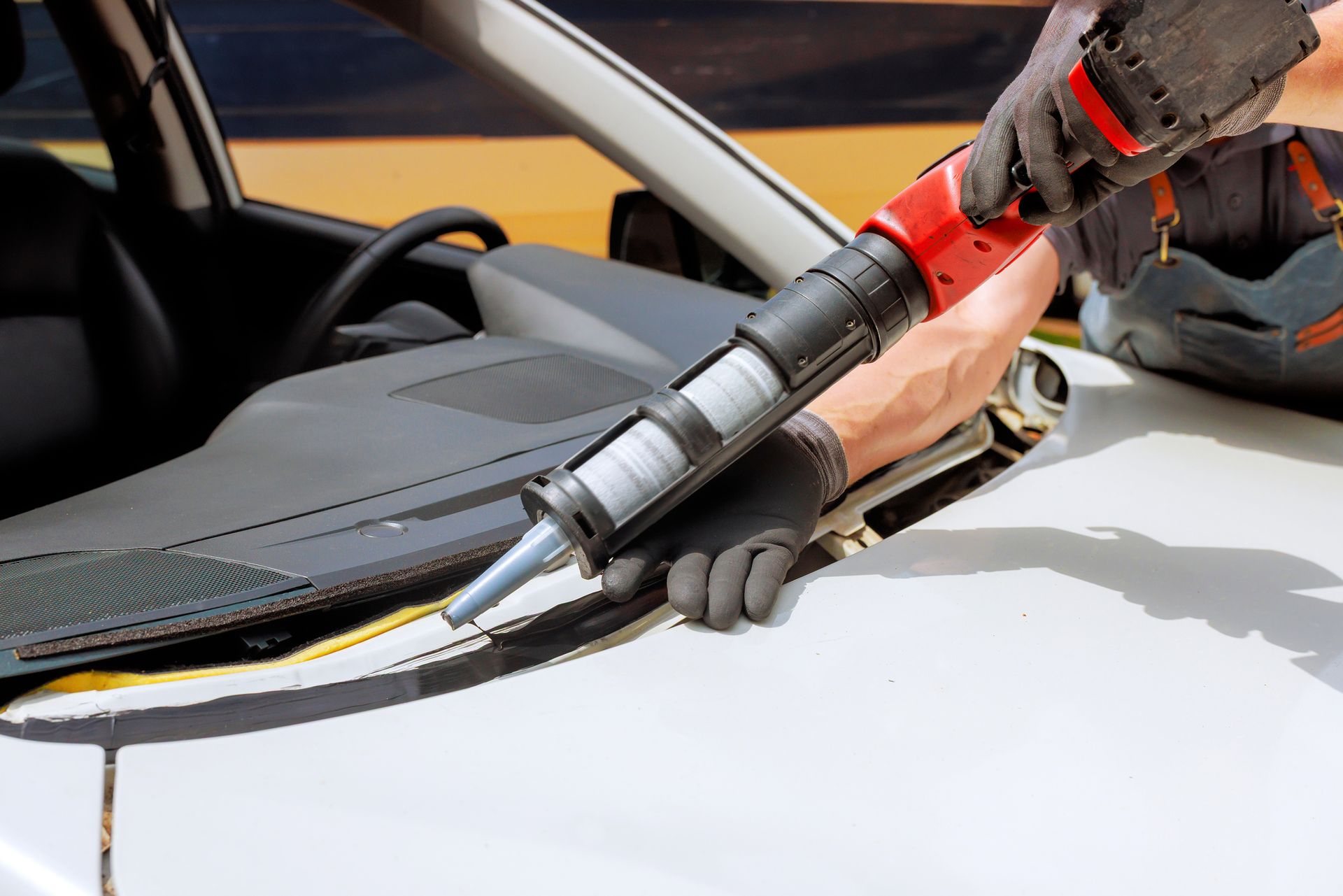 A man is in the process of windshield replacement. A man is in the process of windshield replacement.