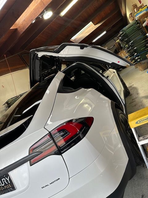 A white tesla model x with its trunk open in a garage.