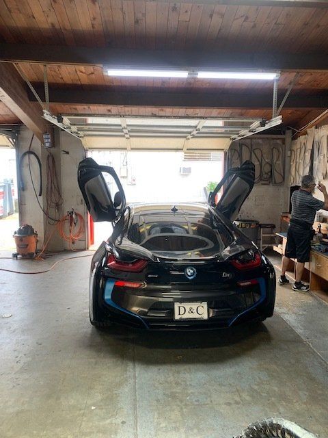 A bmw i8 is parked in a garage with its doors open