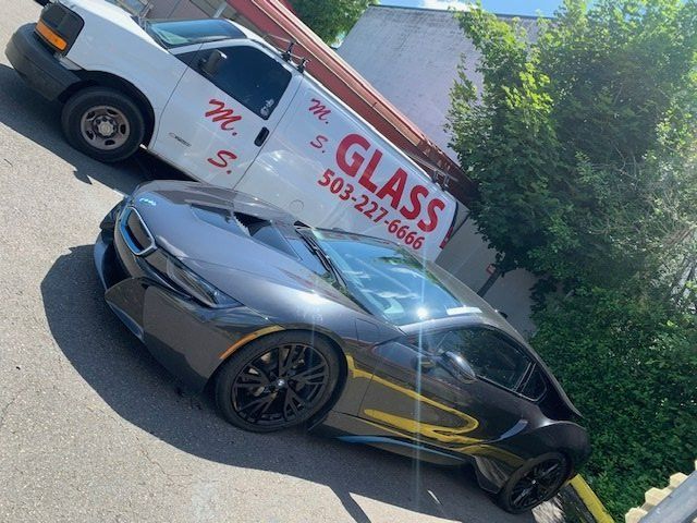 A car is parked next to a van that says glass