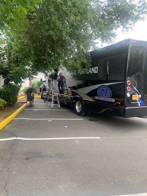 A black bus with the word portland on the side is parked in a parking lot