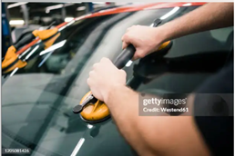 Auto glass replacement process with worker using suction tool to install front windshield.