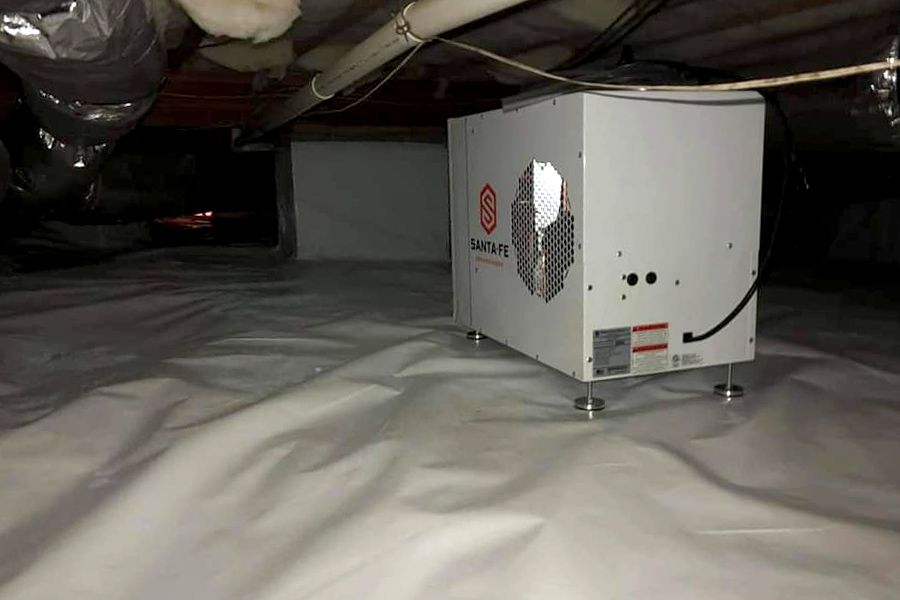 White crawl space with a dehumidifier on white plastic.