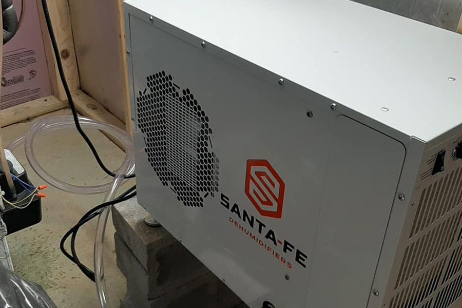 A white Santa Fe dehumidifier with a logo on a concrete block in a room.