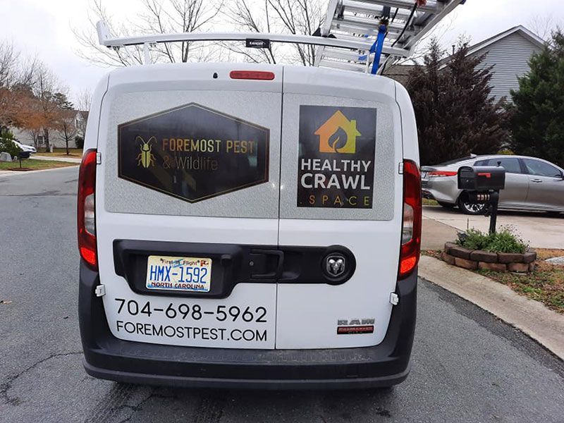 Back of a white van with pest control company logos and contact info.