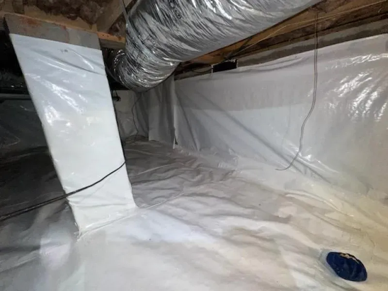 White plastic sheeting lining a crawl space, covering the walls and floor.