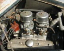 A close up of a car engine with two carburetors