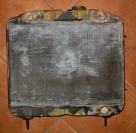 An old radiator is sitting on a tiled floor