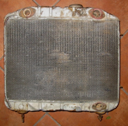 An old radiator is sitting on a tiled floor.