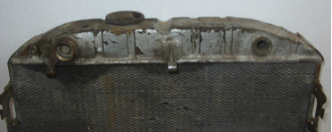 A close up of an old radiator on a white surface.