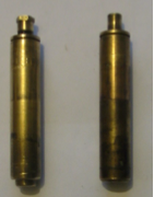 Two brass cylinders are sitting next to each other on a white surface