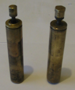 Two brass cylinders are sitting next to each other on a white surface