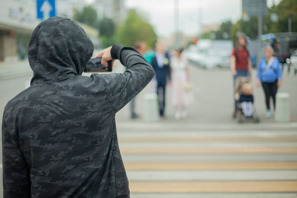 A Man In A Hoodie Is Taking A Picture Of A Crosswalk With A Cell Phone — Surveillance NQ In Aitkenvale, QLD