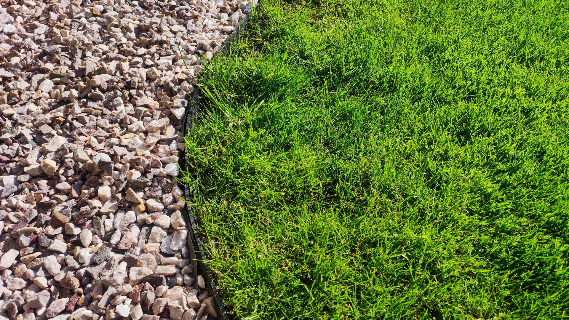 Border of tan gravel and green grass.