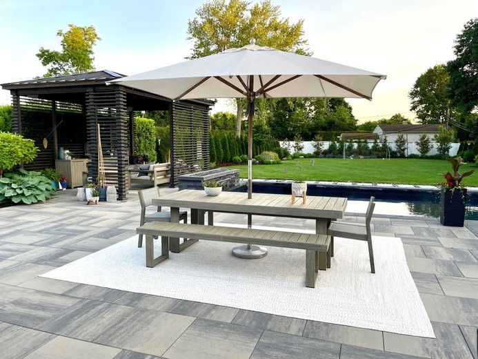 Patio with dining set, umbrella, and pool; lawn and garden in the background.
