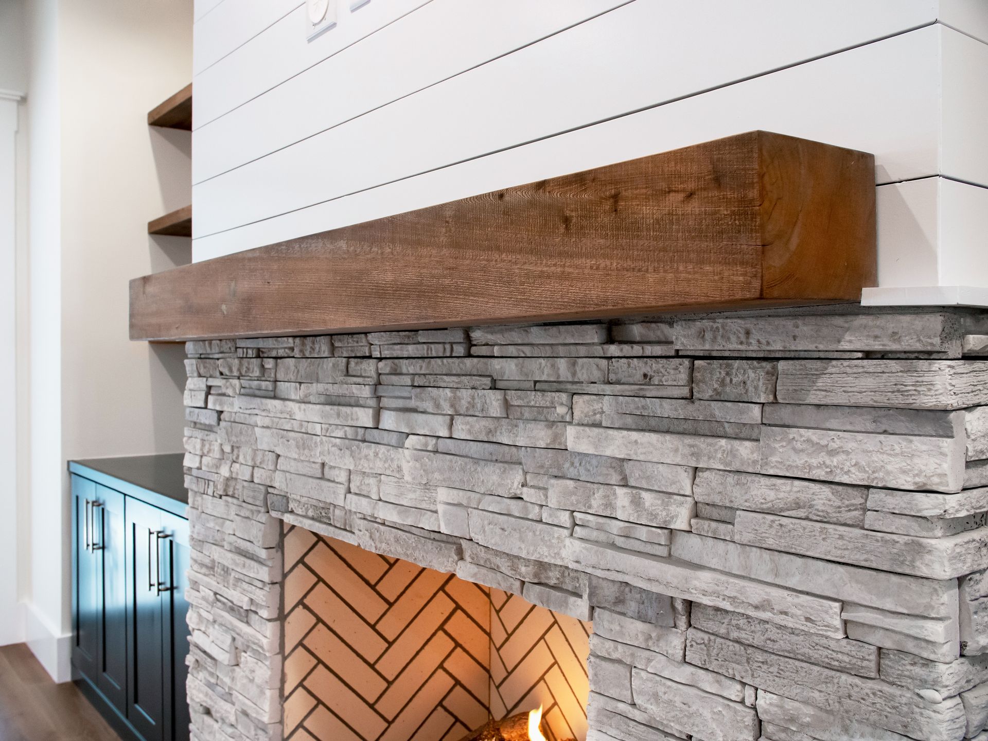 Stone fireplace with wooden mantel and herringbone brick interior.