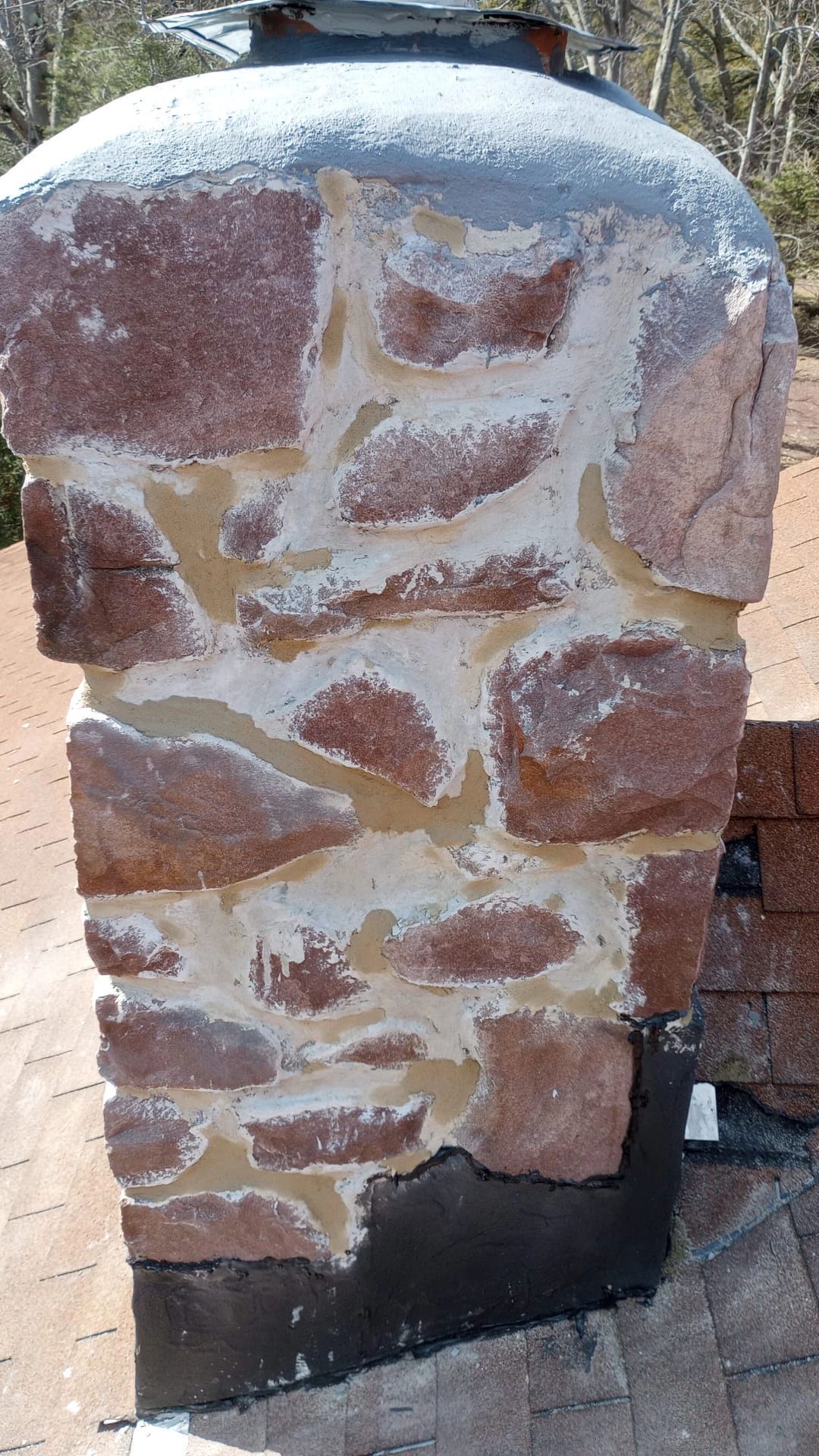 Stone chimney with light-colored mortar; the top is gray, and the bottom is black.