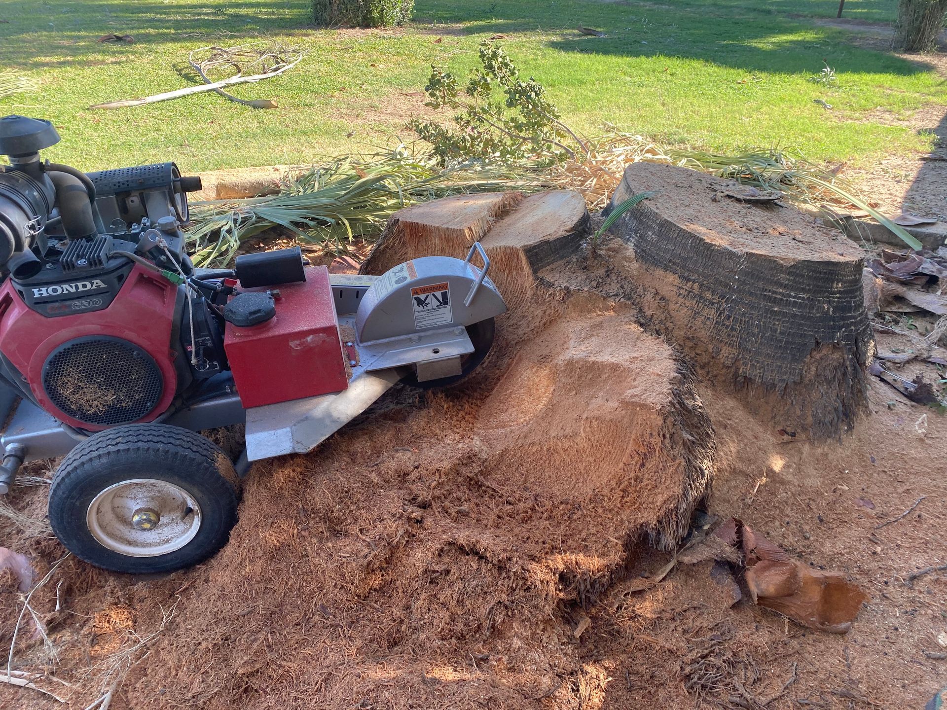 A honda lawn mower is sitting next to a tree stump.