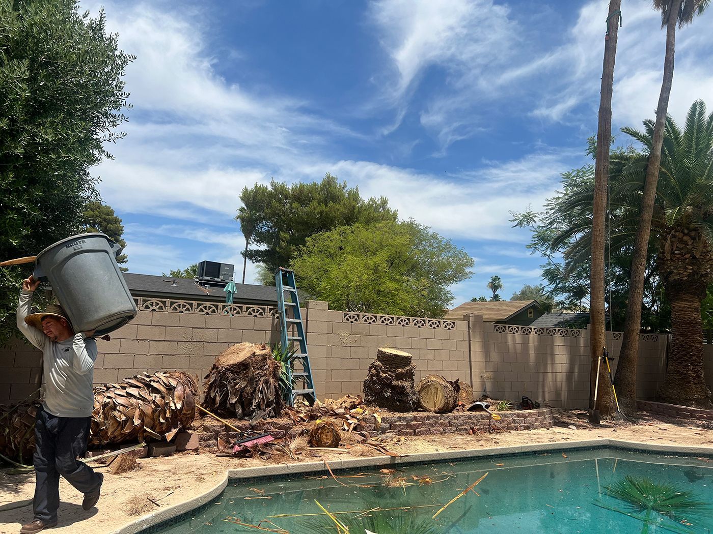 A man is carrying a bucket over his head next to a pool.