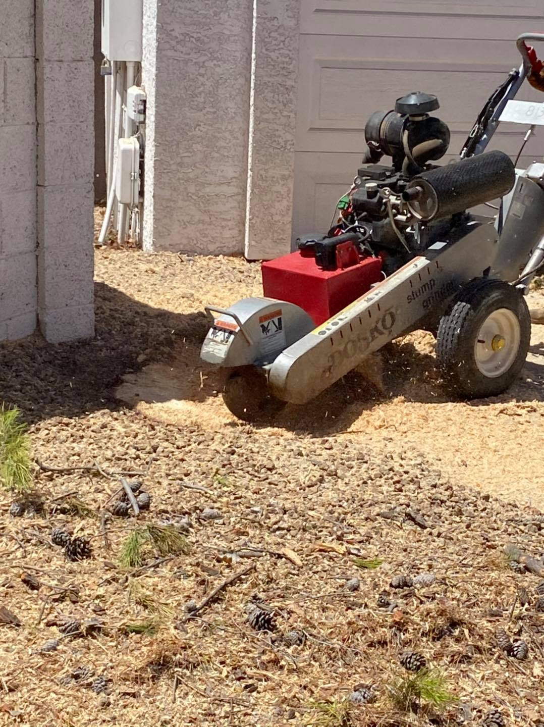 A lawn mower is parked in the dirt in front of a garage.