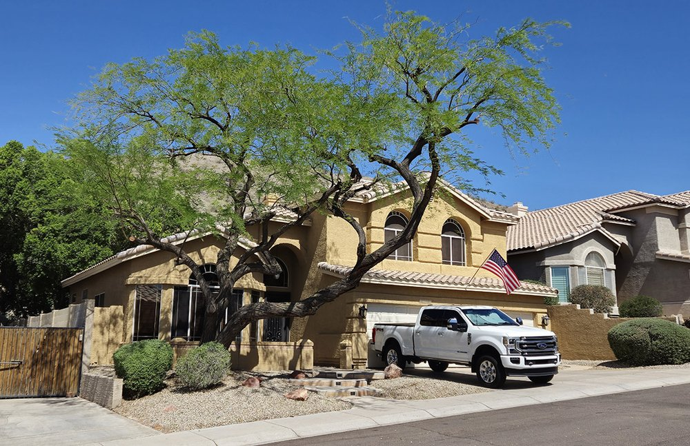 A white truck is parked in front of a large house.