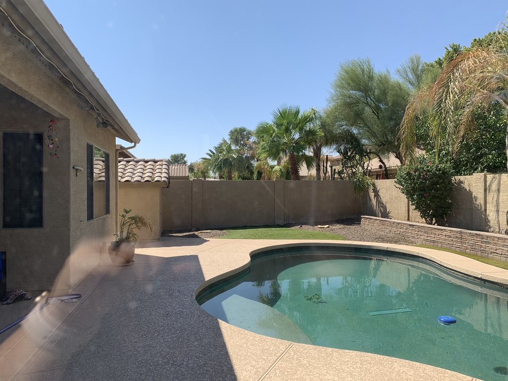 A large swimming pool is in the backyard of a house.