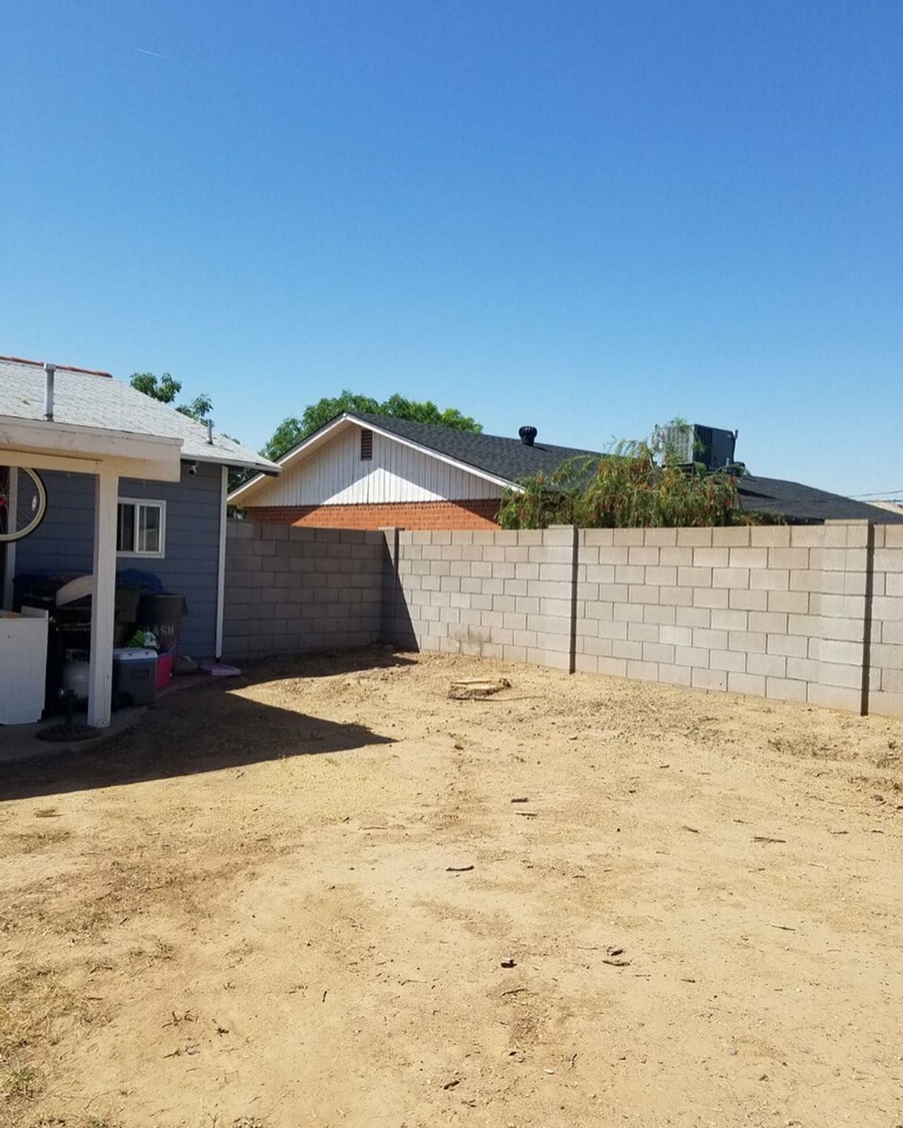 A backyard with a brick wall and a house in the background
