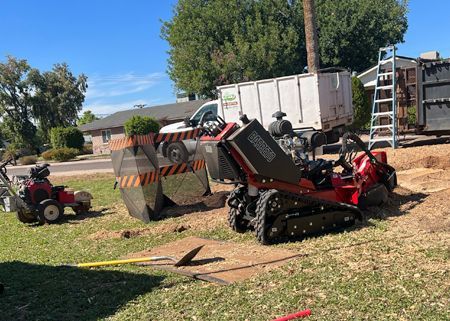 A stump grinder is being used to remove a tree stump in a yard.