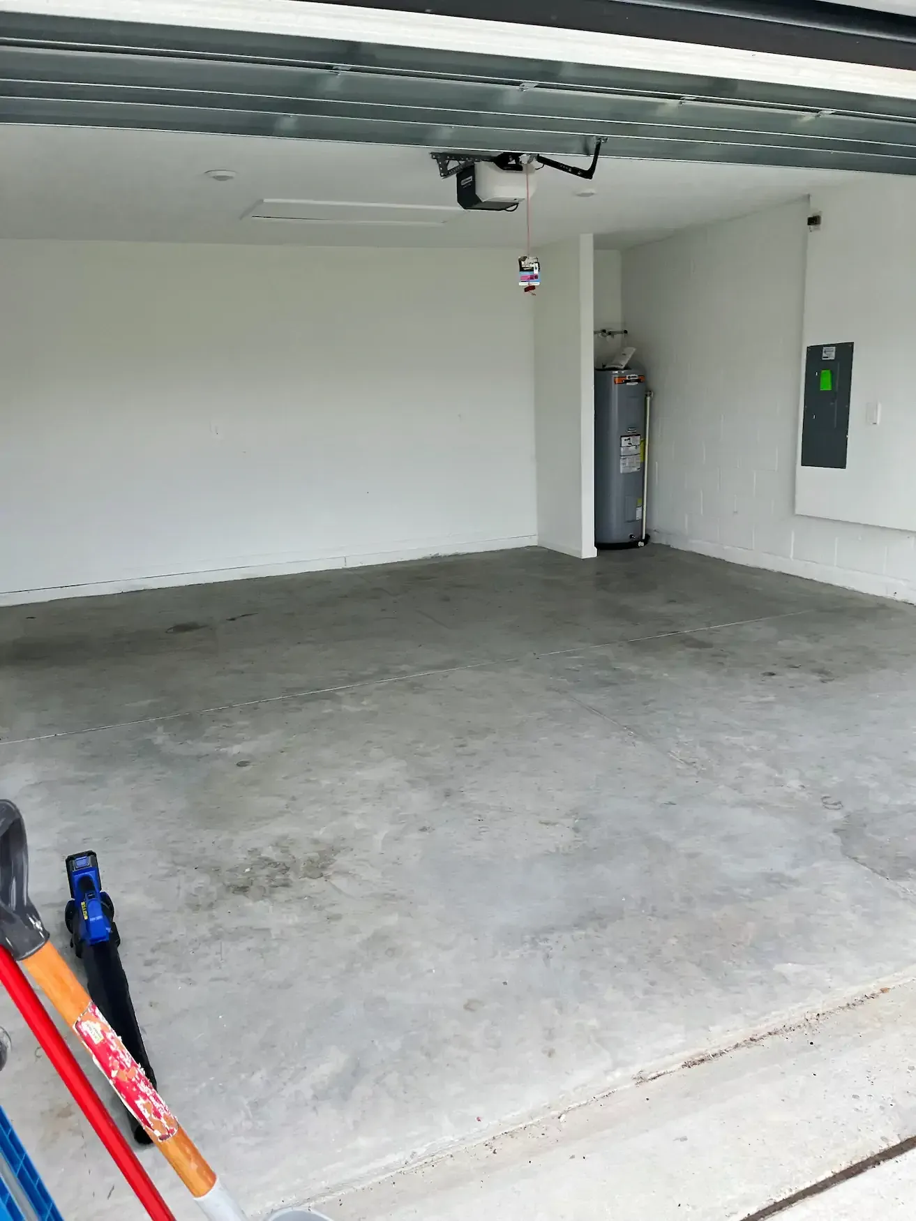 Empty garage interior with concrete floor, white walls, and a water heater.