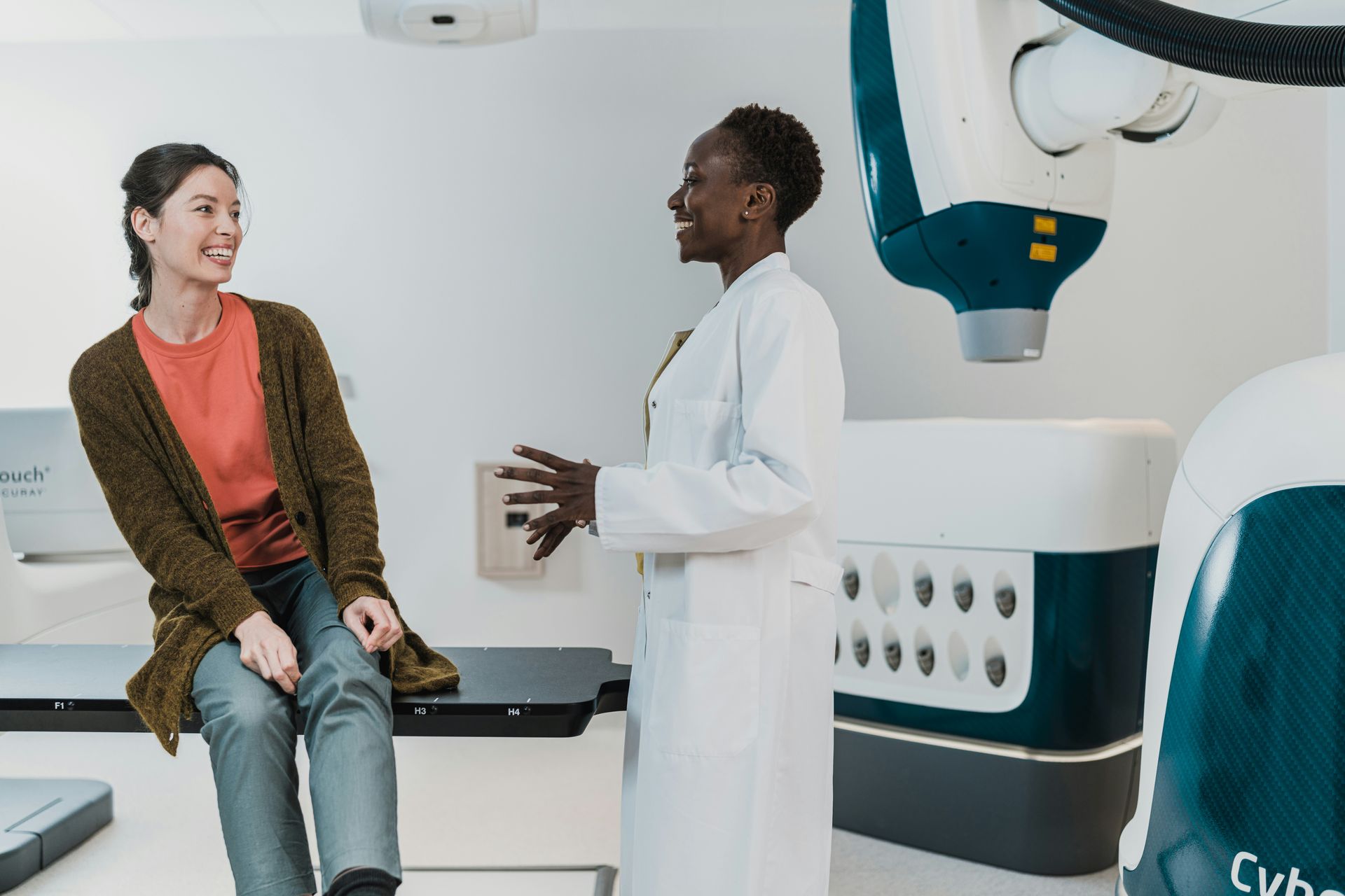 Patient talking with doctor in a modern medical imaging room, with a CT scanner beside them