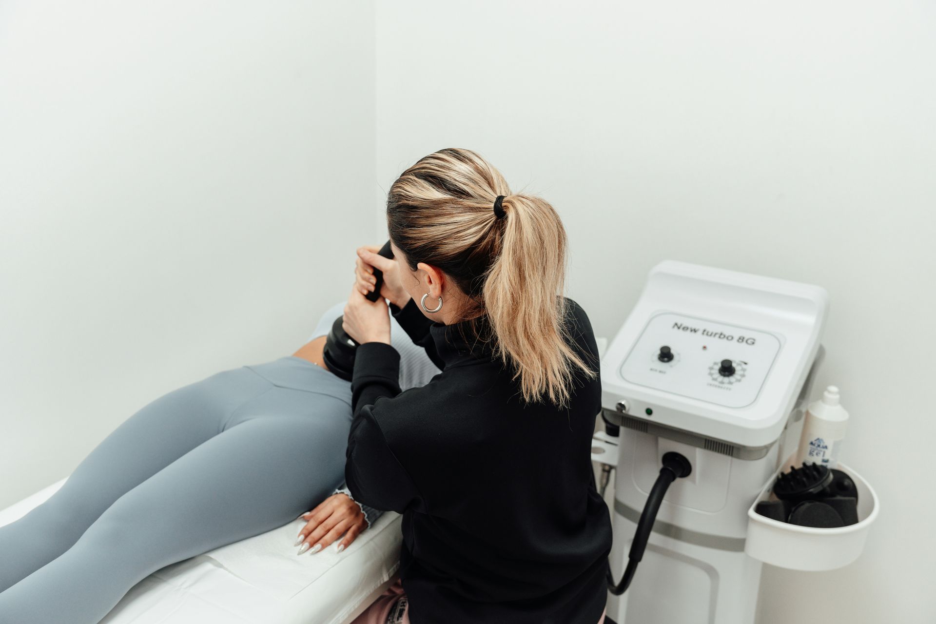 Clinician using a handheld device on a patient’s leg in a white treatment room