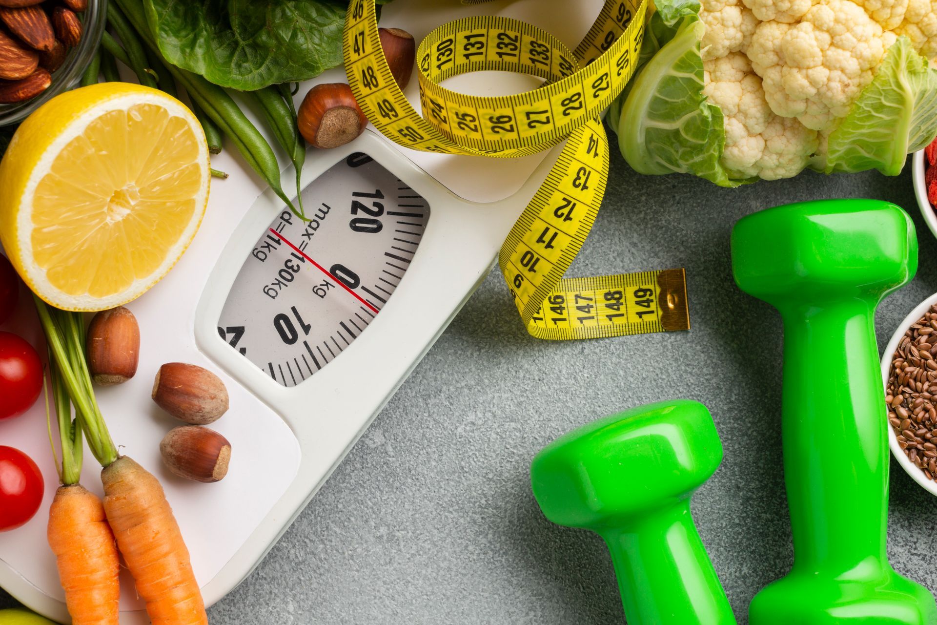 Fitness and diet concept with scale, fruits, vegetables, measuring tape, and dumbbells
