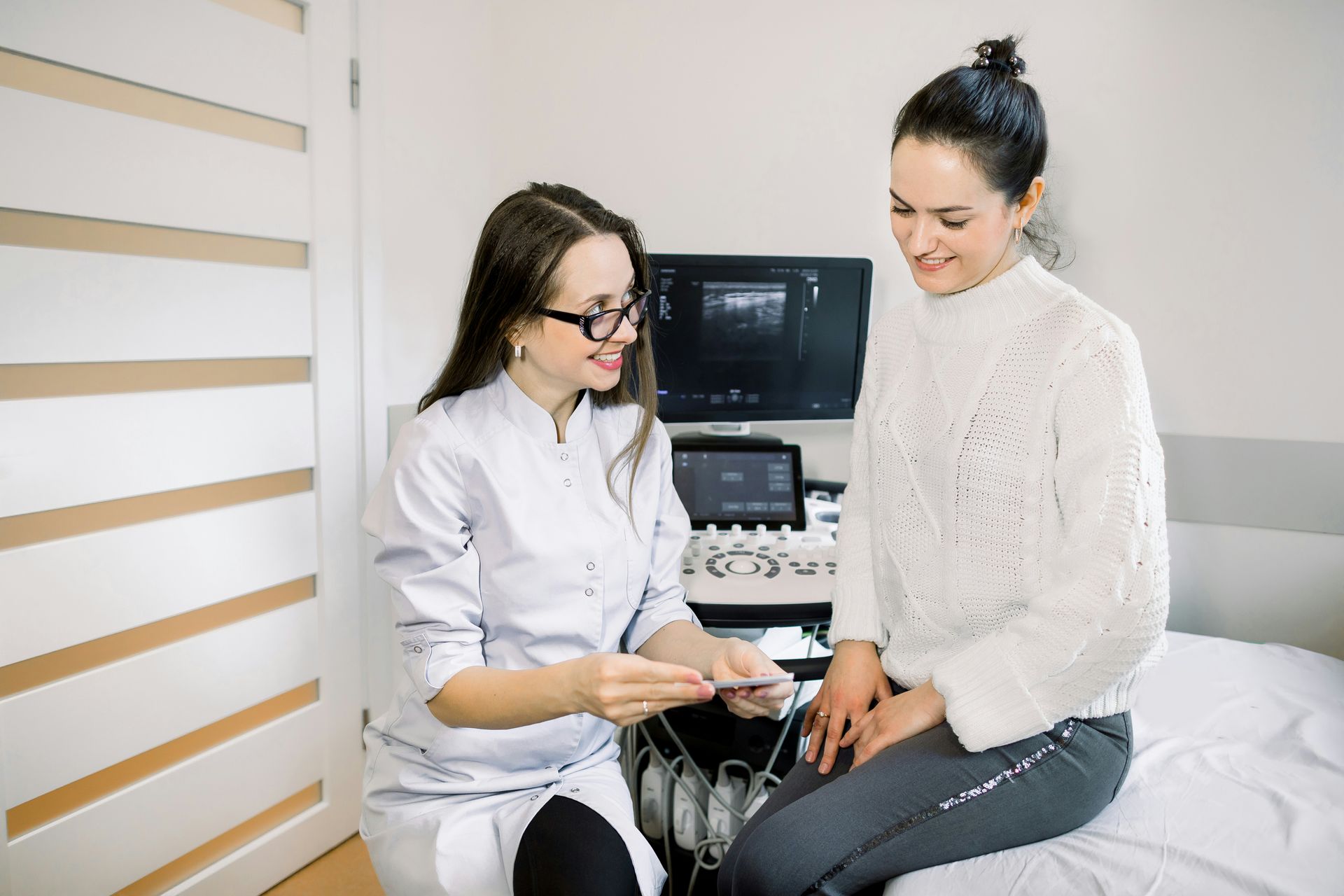 Doctor showing ultrasound to a patient in a bright exam room
