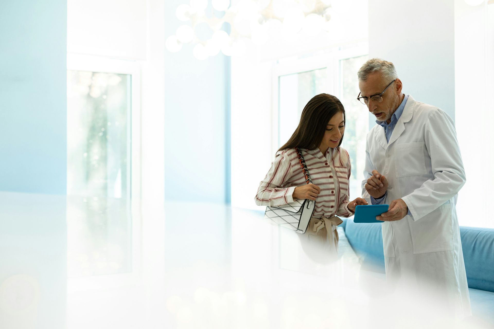 Doctor showing a patient a clipboard in a bright hospital hallway