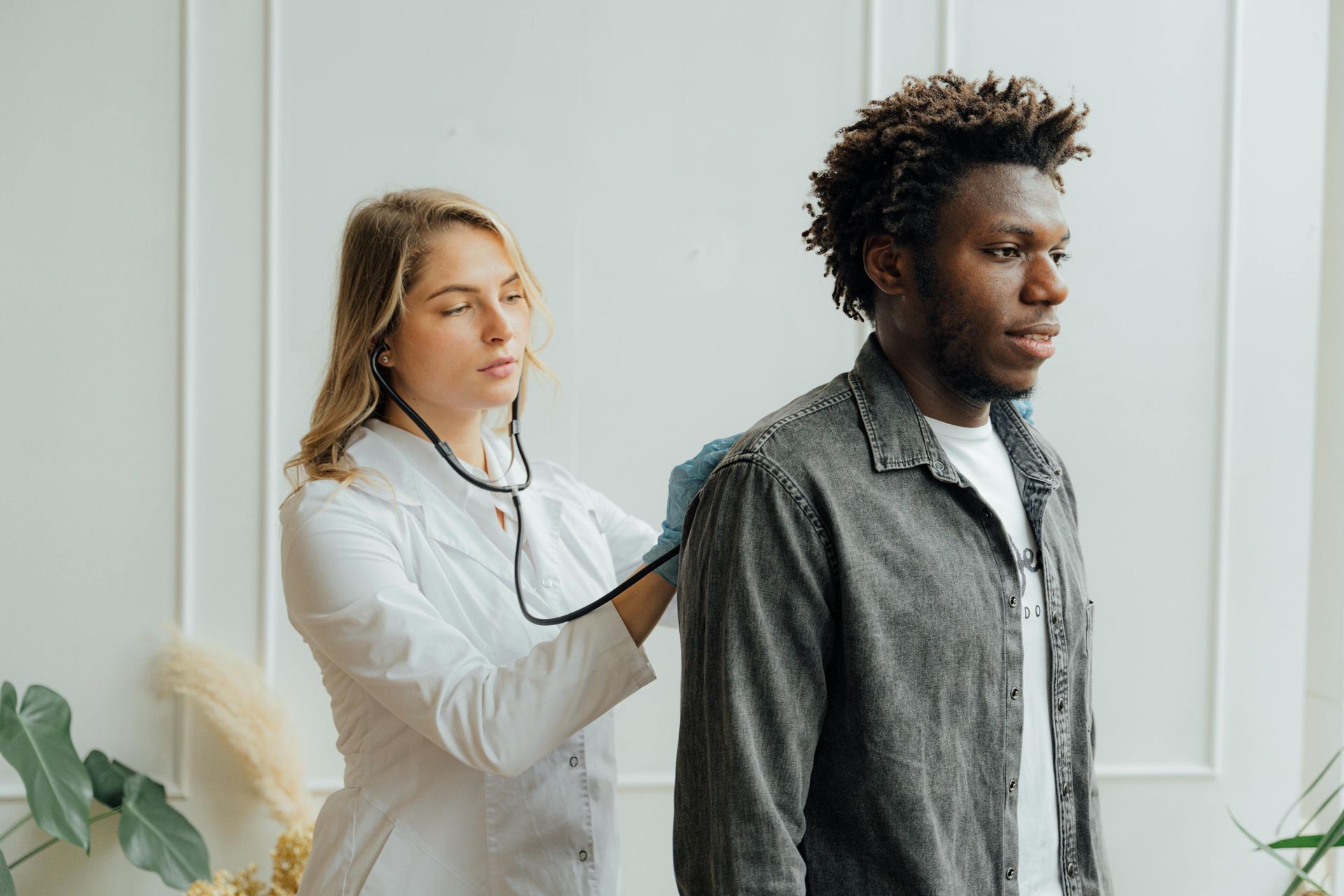 Doctor listening to a patient’s back with a stethoscope in a bright clinic room