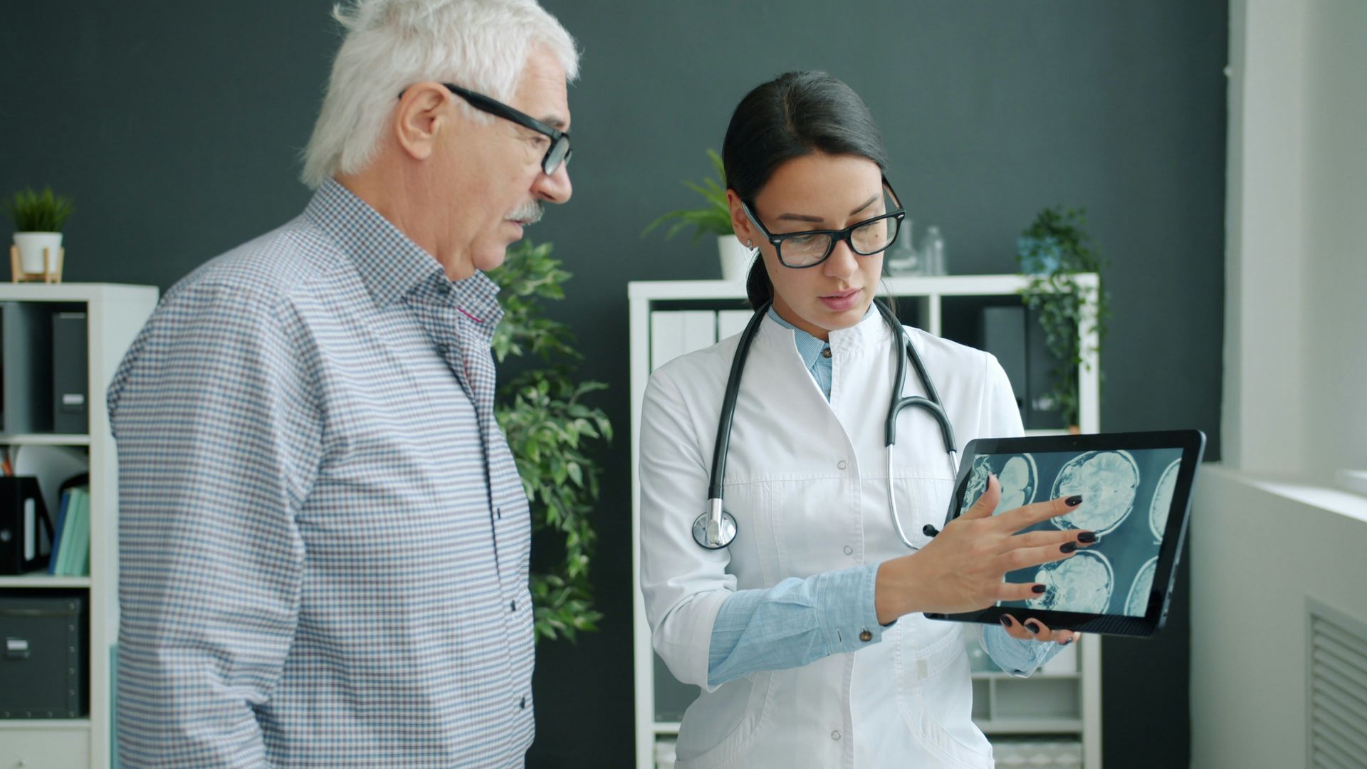 Doctor showing medical scan on tablet to a man in a clinic office