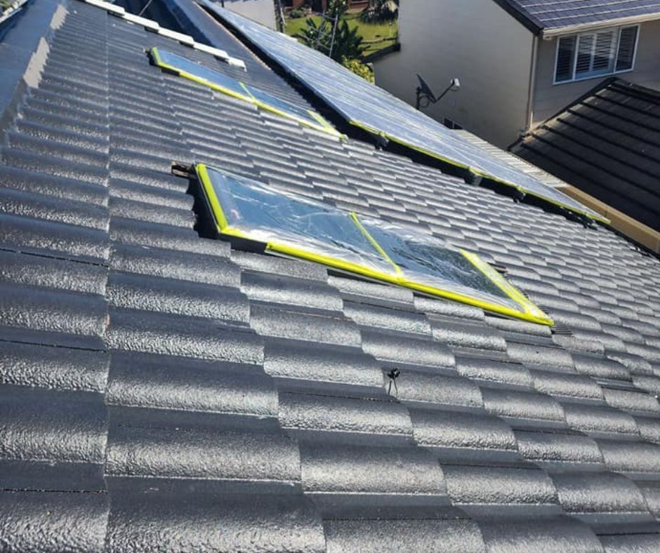 Solar panels on a dark gray tiled roof in a residential neighborhood.
