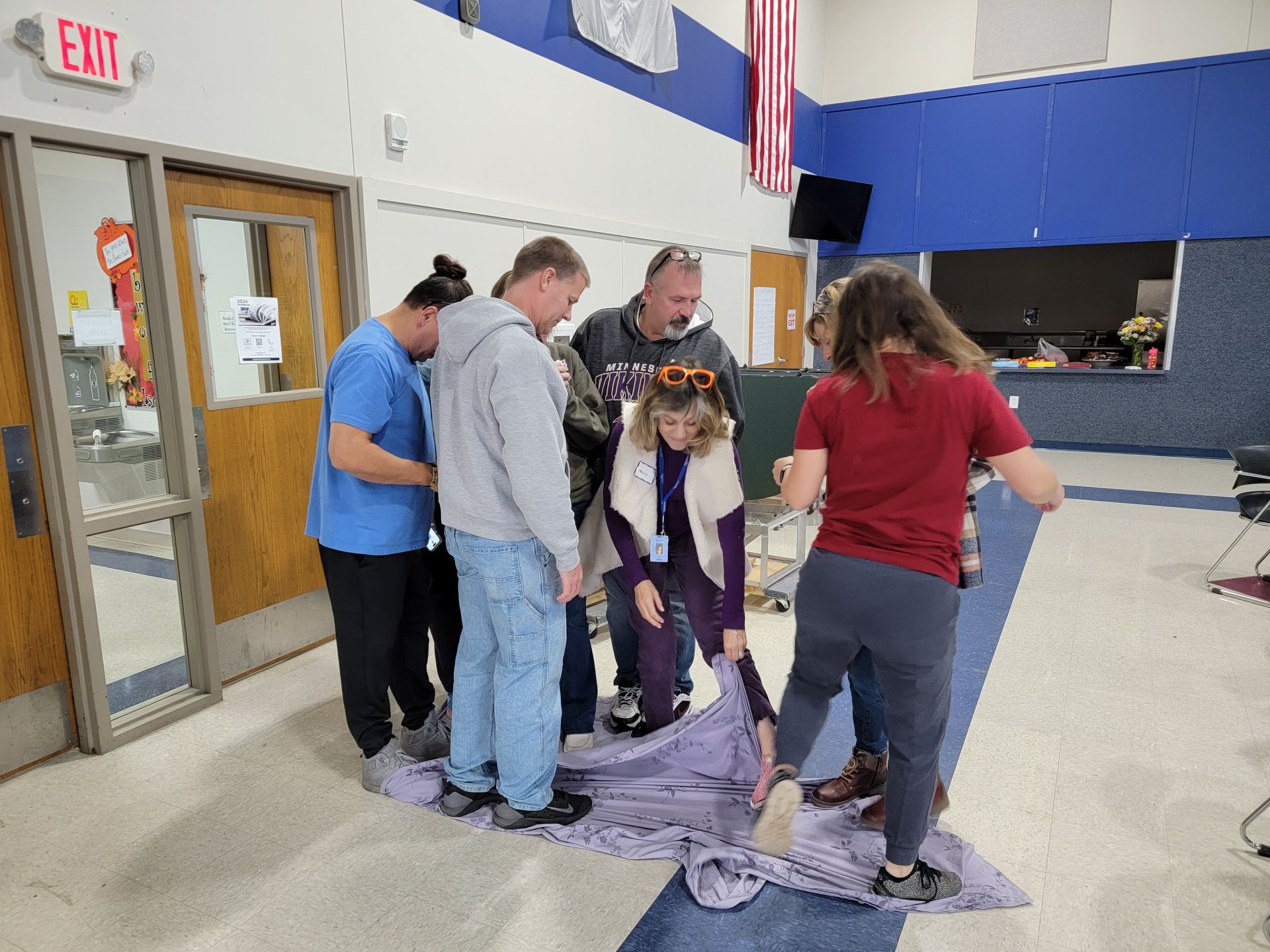 A group of people are standing around a blanket in a room.