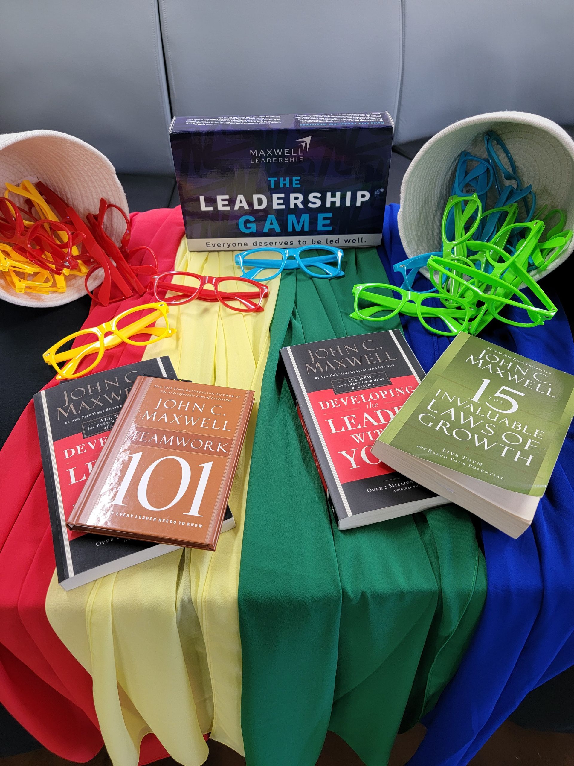 A table topped with books , glasses , and a box of the leadership game.