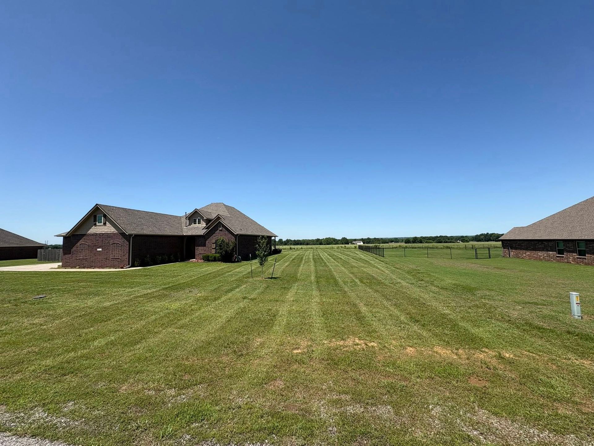 Brick houses on a green lawn with a clear blue sky in a rural setting.