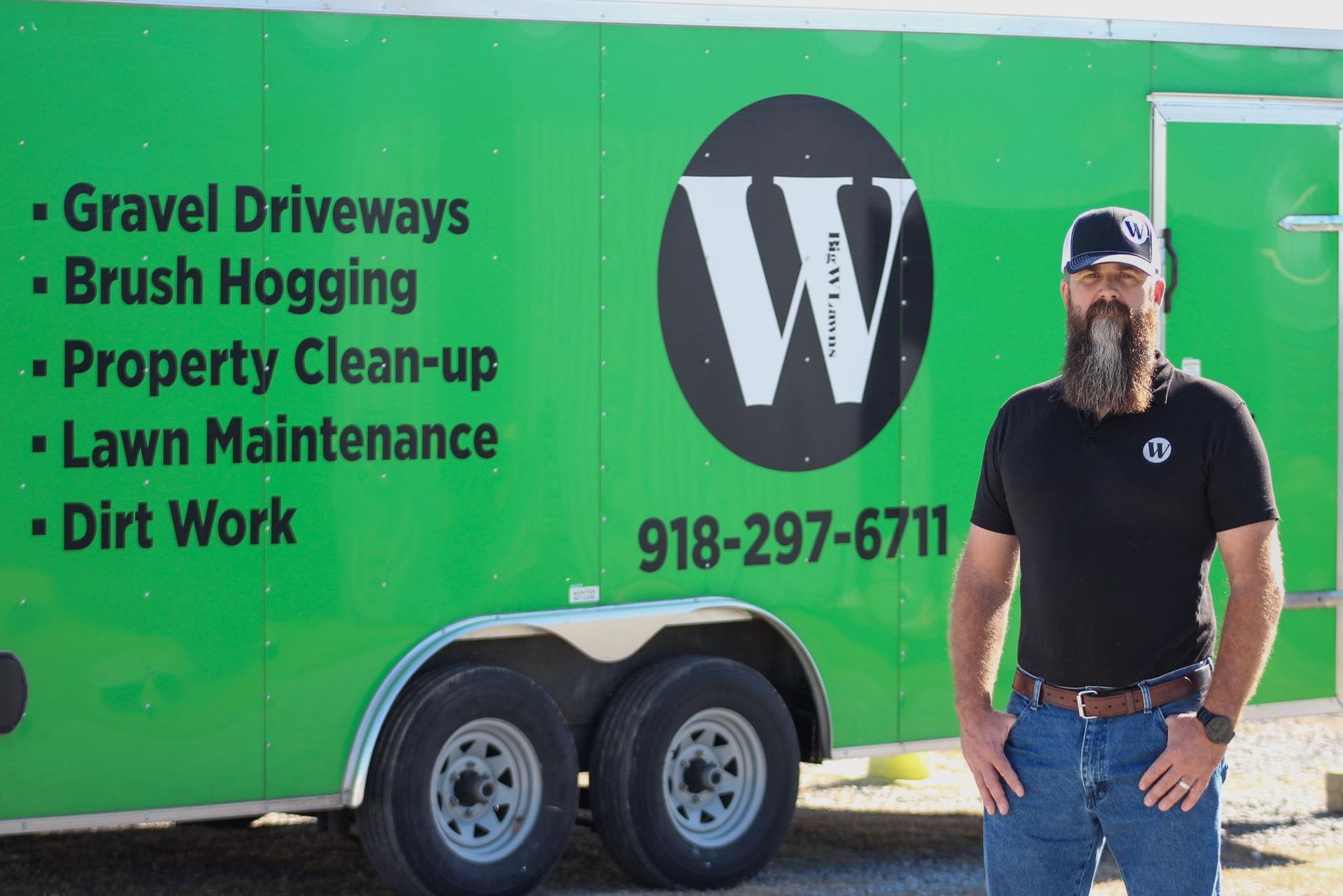 A man stands in front of a green trailer with 
