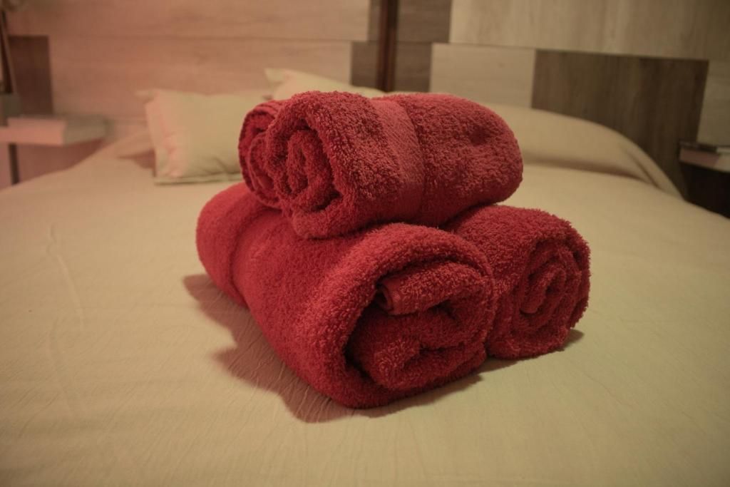 Tres toallas rojas están apiladas una encima de otra sobre una cama.