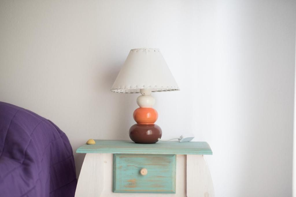 Una lámpara está sobre una mesita de noche al lado de una cama.