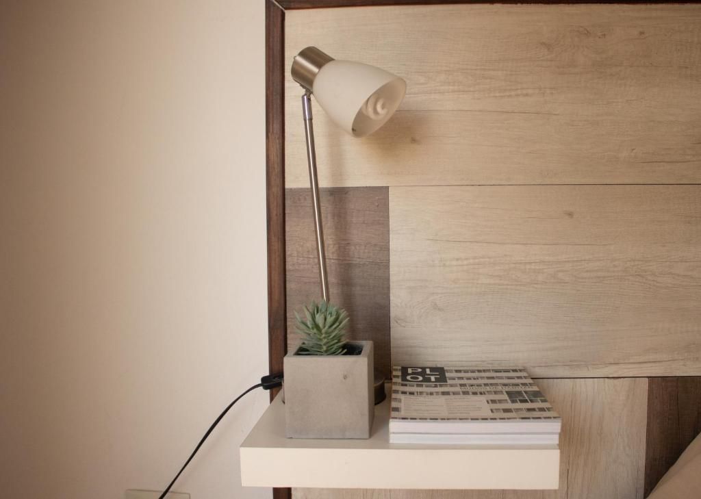 Una lámpara está en un estante al lado de un libro.