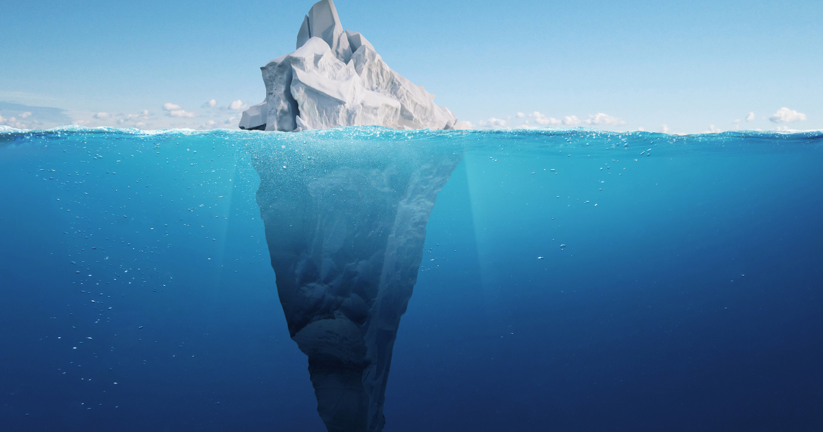 Iceberg floating in ocean, visible portion above water, large submerged portion below.