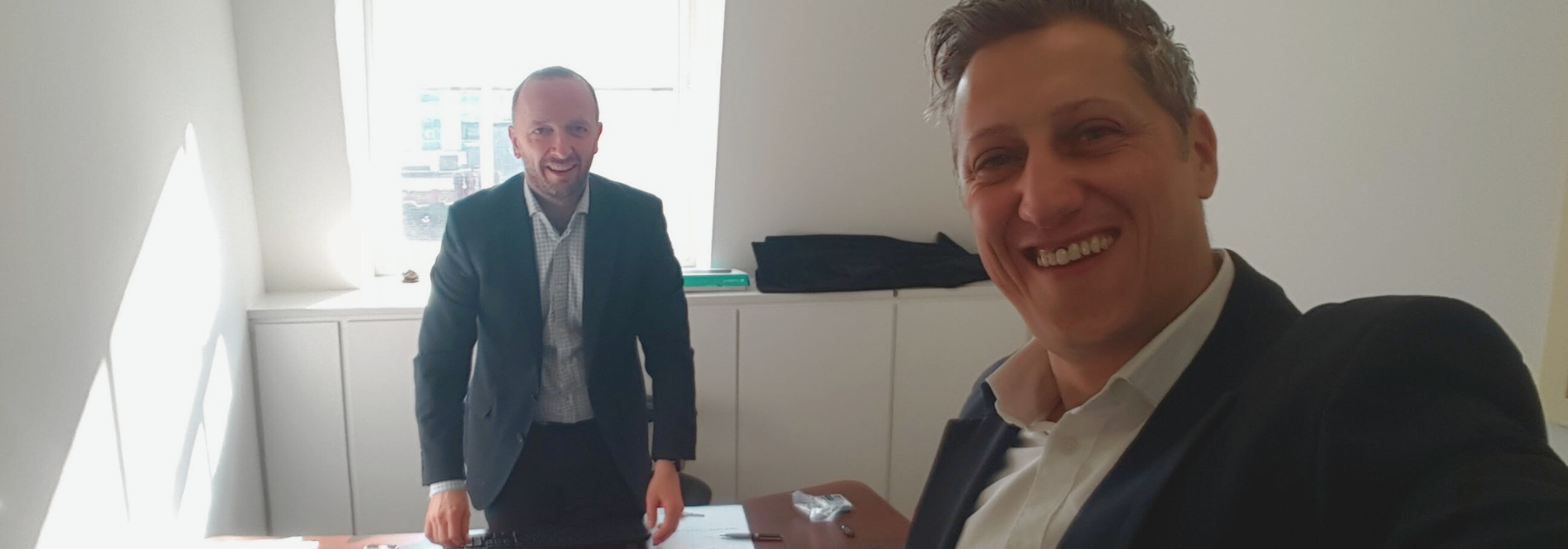 2 men in suits in a small white office