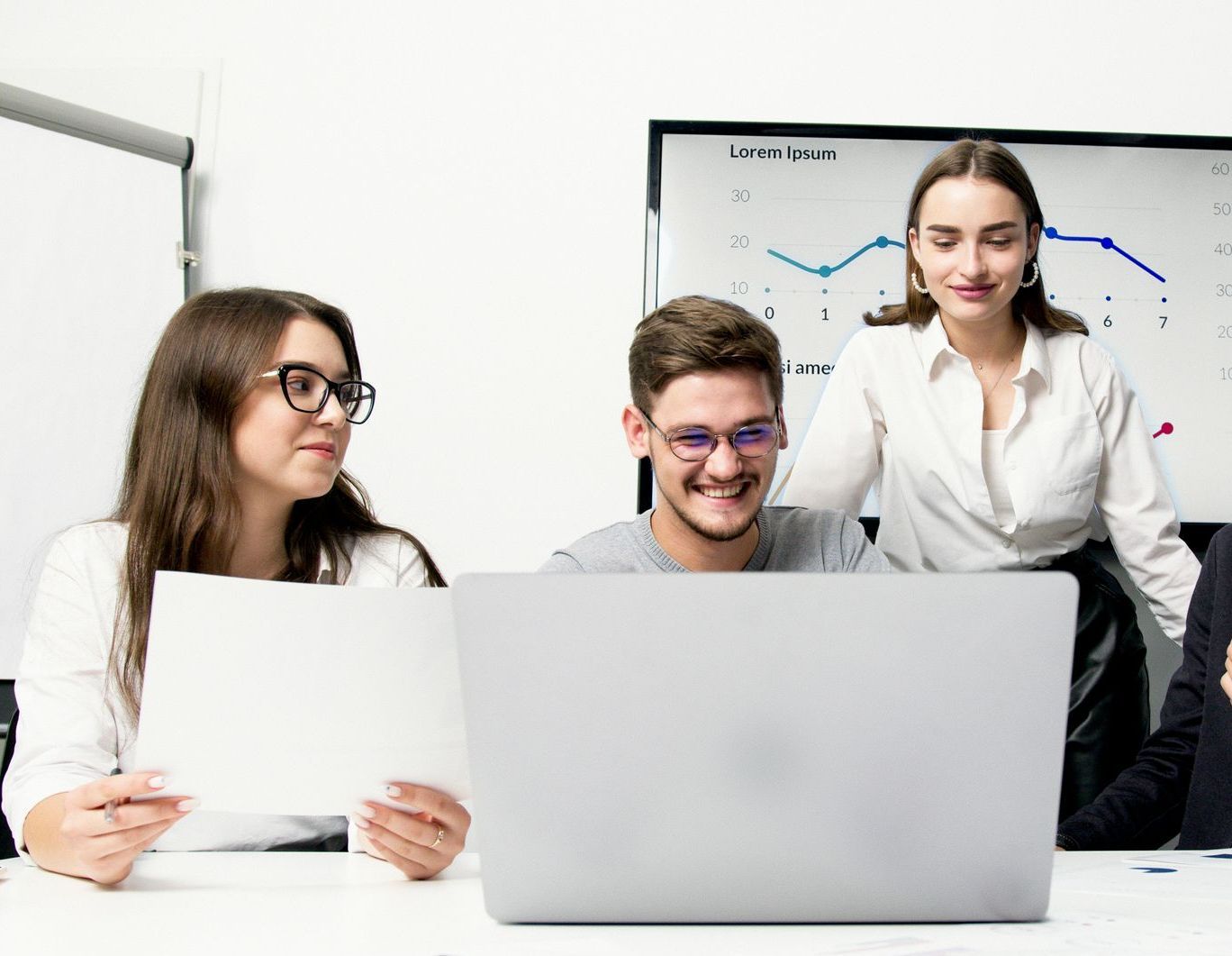 A group of people are sitting at a table looking at a laptop computer.