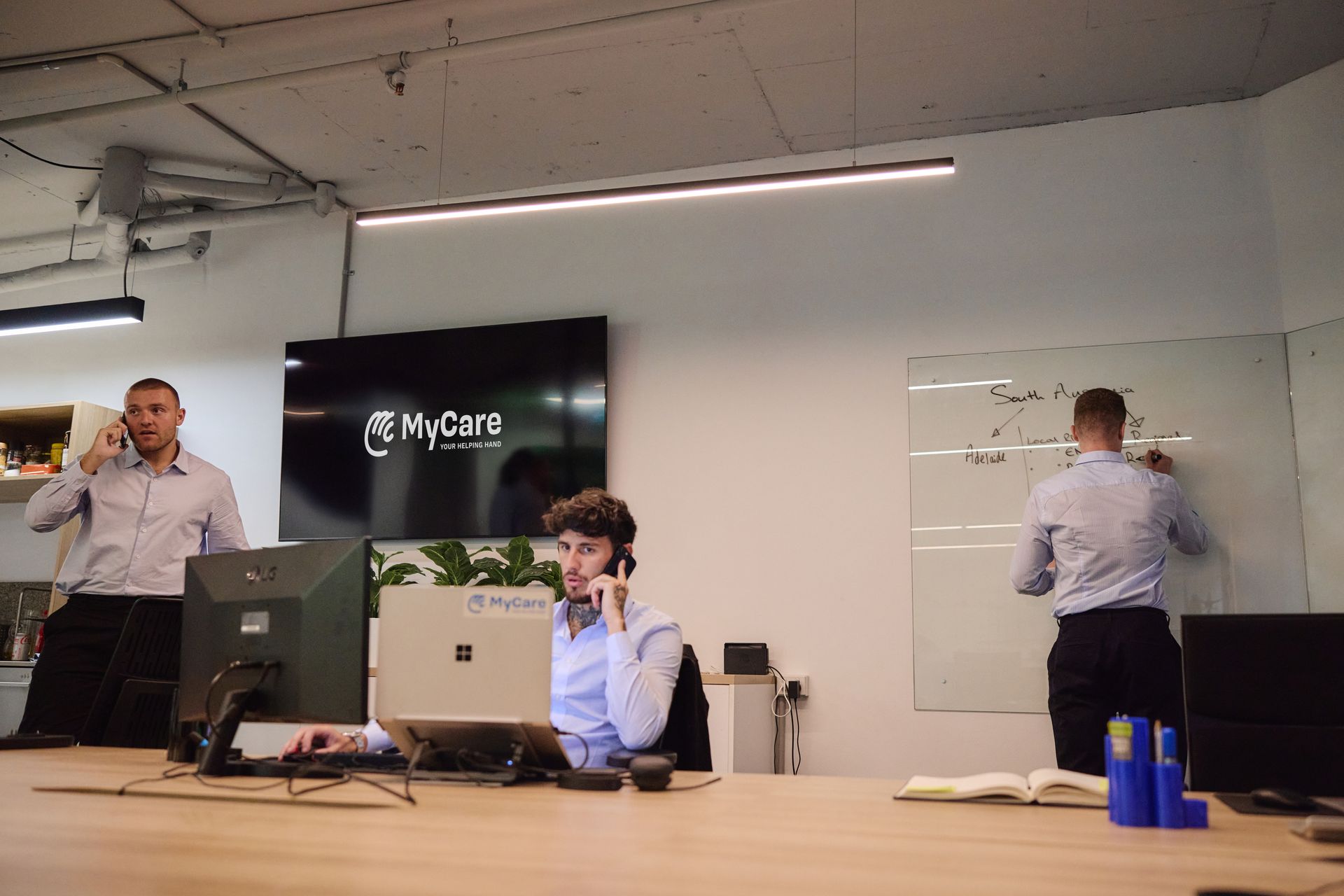 A group of people are sitting at a table looking at a laptop computer.