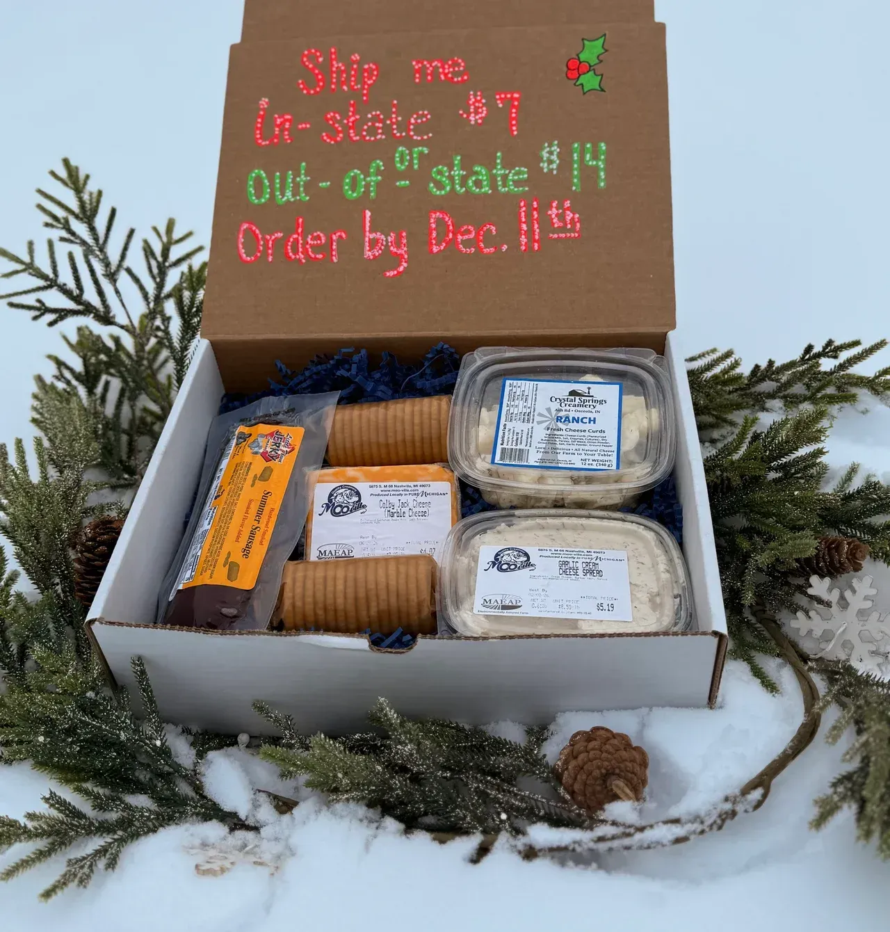 Gift box with food items on a snowy surface, text: